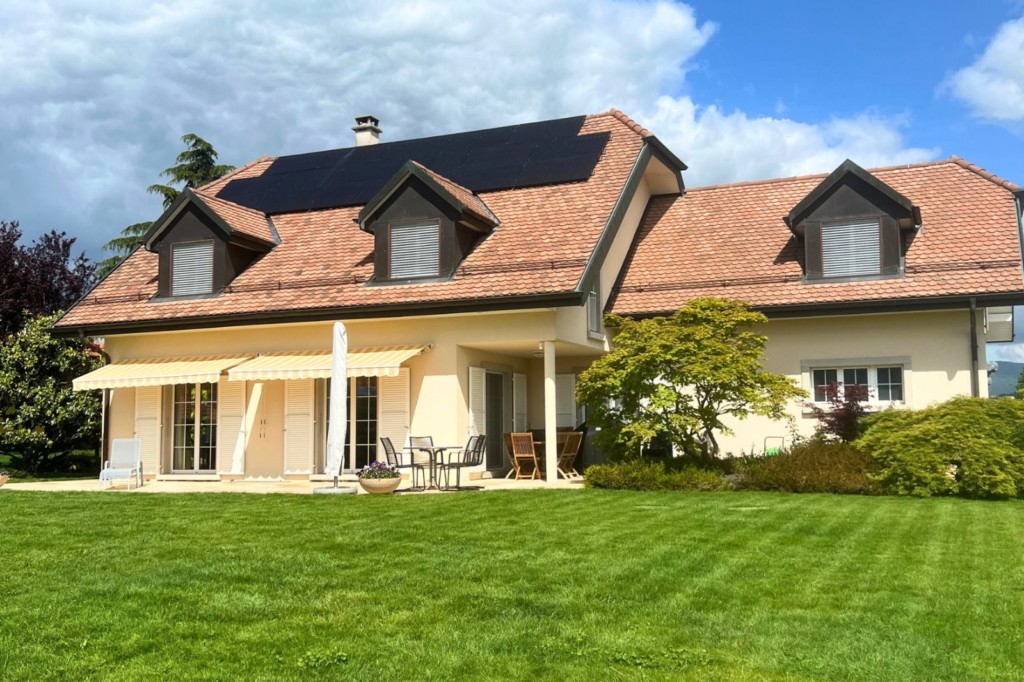 Vue jardin de la maison rénovée avec panneaux photovoltaïques à Denens