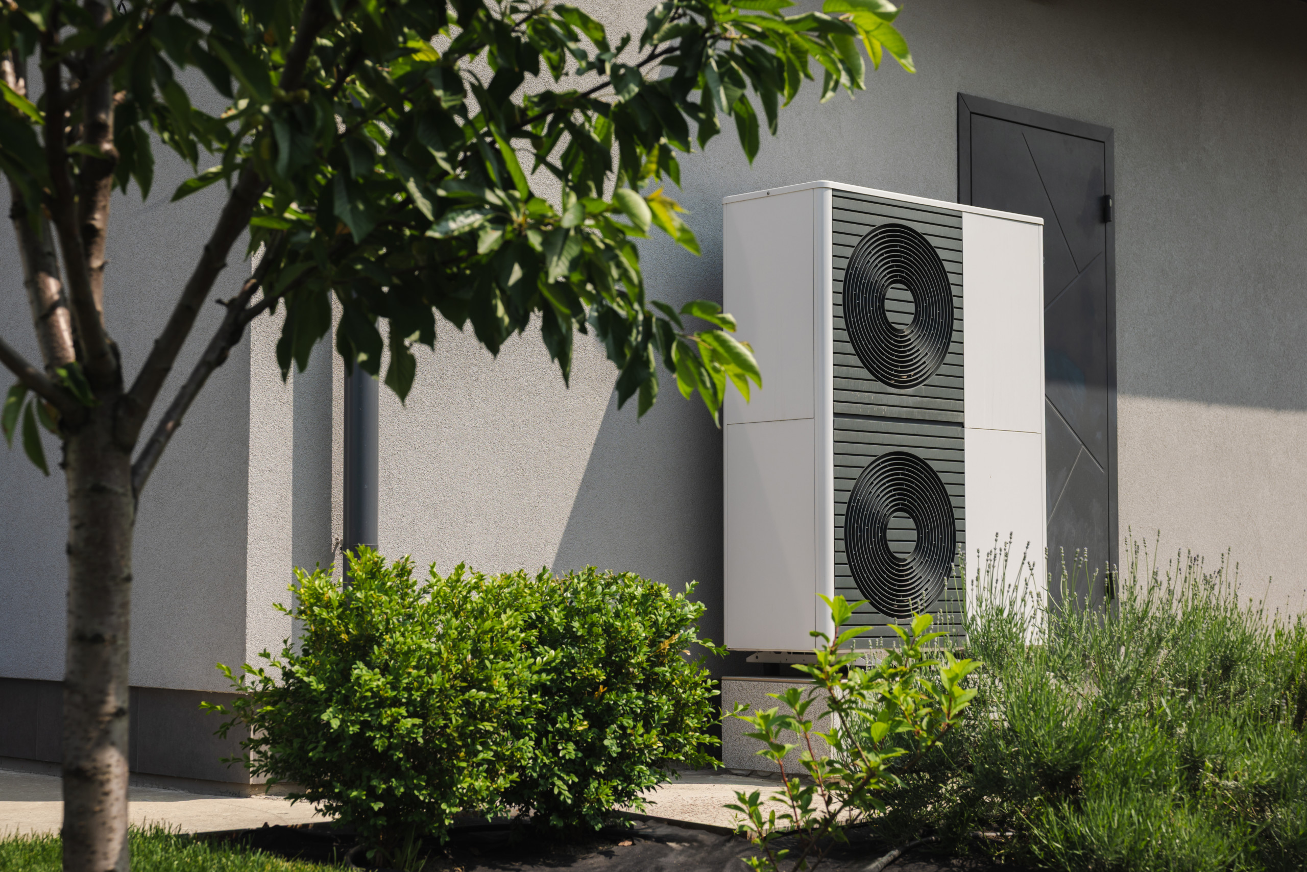 Unité extérieure de climatisation réversible installée contre la façade d’une maison
